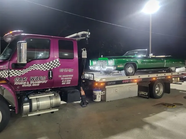 Car Wars flatbed tow truck transporting a teal Chevy pickup truck in Orange, TX