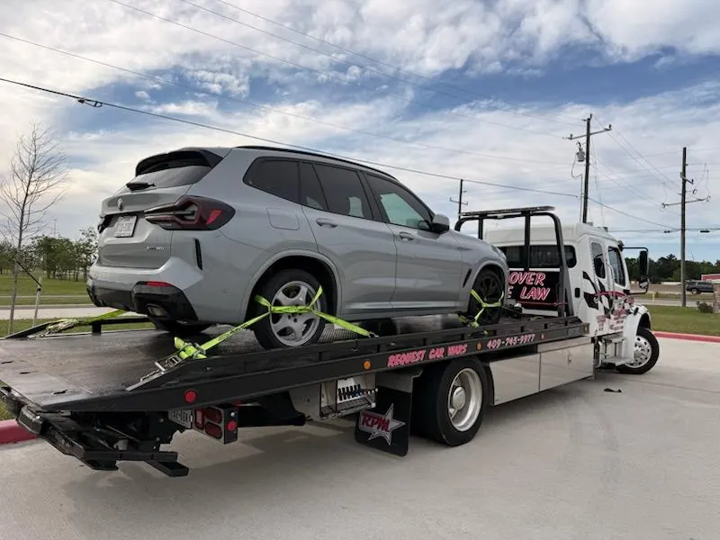 Car Wars Towing flatbed tow truck transporting a gray BMW SUV in Orange, TX