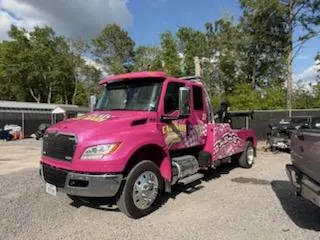 Karl, owner of Car Wars Towing, with shop dog in front of pink tow truck in Orange, TX