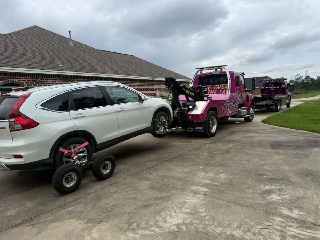 Pink Car Wars tow truck at vehicle recovery scene with crew in Orange, TX